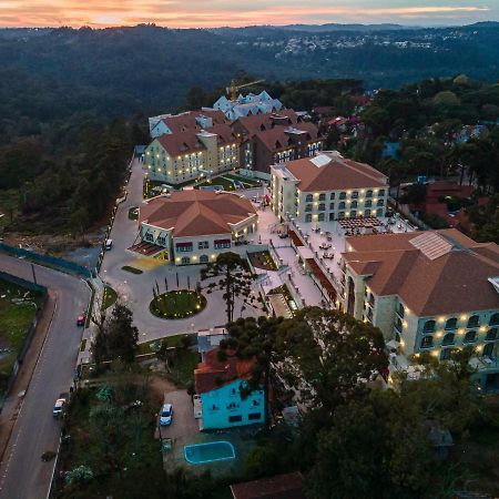 Buona Vitta Gramado Resort & Spa By Gramado Parks Exterior foto The photo shows an aerial view of a hotel complex set in a hilly, wooded area. The buildings feature a mix of architectural styles with several structures, including a central round pavilion. Surrounding the buildings are well-maintained gardens and 