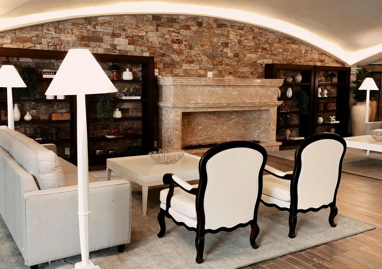 Buona Vitta Gramado Resort & Spa By Gramado Parks Exterior foto The photo shows a stylish living room with a modern design. In the center, there is a light-colored sofa and two elegant white armchairs with black wooden frames. A coffee table is placed in front of the sofa. Behind them, there is a large, decorativ