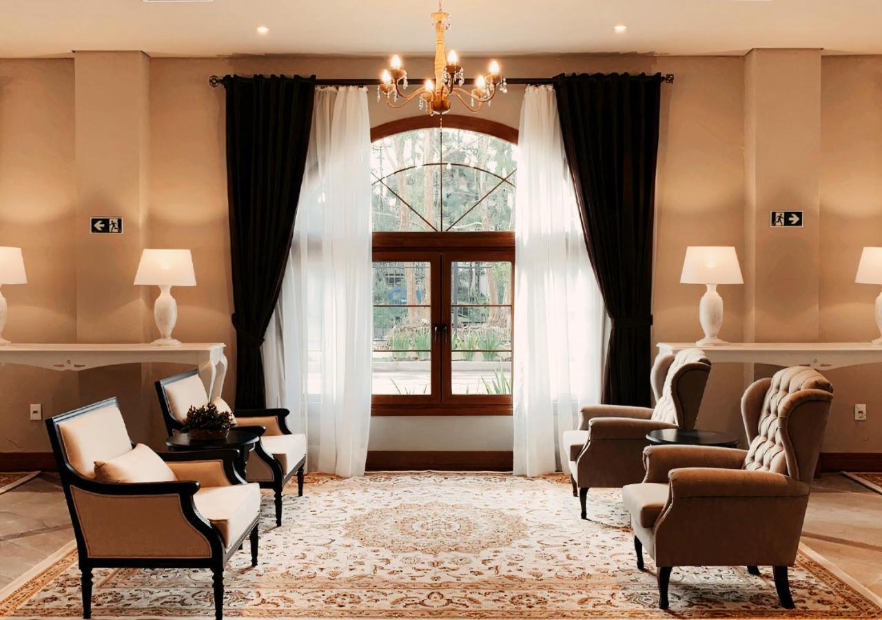 Buona Vitta Gramado Resort & Spa By Gramado Parks Exterior foto The photo shows an elegantly styled living room. There are two armchairs and a sofa arranged comfortably around an intricate area rug. Large windows are adorned with sheer white curtains and dark curtains, allowing natural light to fill the space. A 
