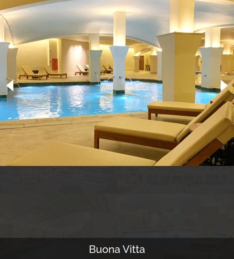 Buona Vitta Gramado Resort & Spa By Gramado Parks Exterior foto The photo shows a tranquil indoor pool area, featuring a large swimming pool with clear blue water. Surrounding the pool are several lounge chairs made of light-colored wood, positioned for relaxation. The space is well-lit, with soft lighting highli
