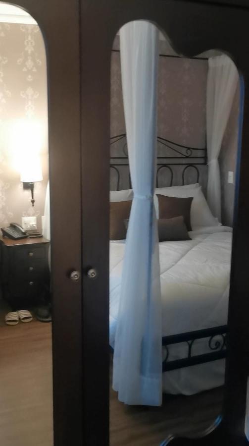 Buona Vitta Gramado Resort & Spa By Gramado Parks Exterior foto The photo shows a cozy bedroom scene. It features a bed with white bedding and several brown accent pillows. The bed is framed by a decorative headboard and appears to be situated against a wall with subtle patterns. Next to the bed, there is a night
