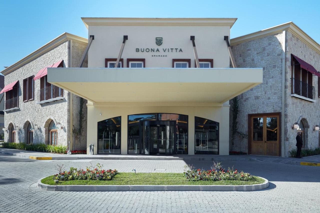 Buona Vitta Gramado Resort & Spa By Gramado Parks Exterior foto The photo shows a modern building with a prominent entrance marked by a large awning. The facade features a mix of stone and stucco materials, giving it an elegant and contemporary look. The name "BUONA VITTA" is displayed prominently above the entra
