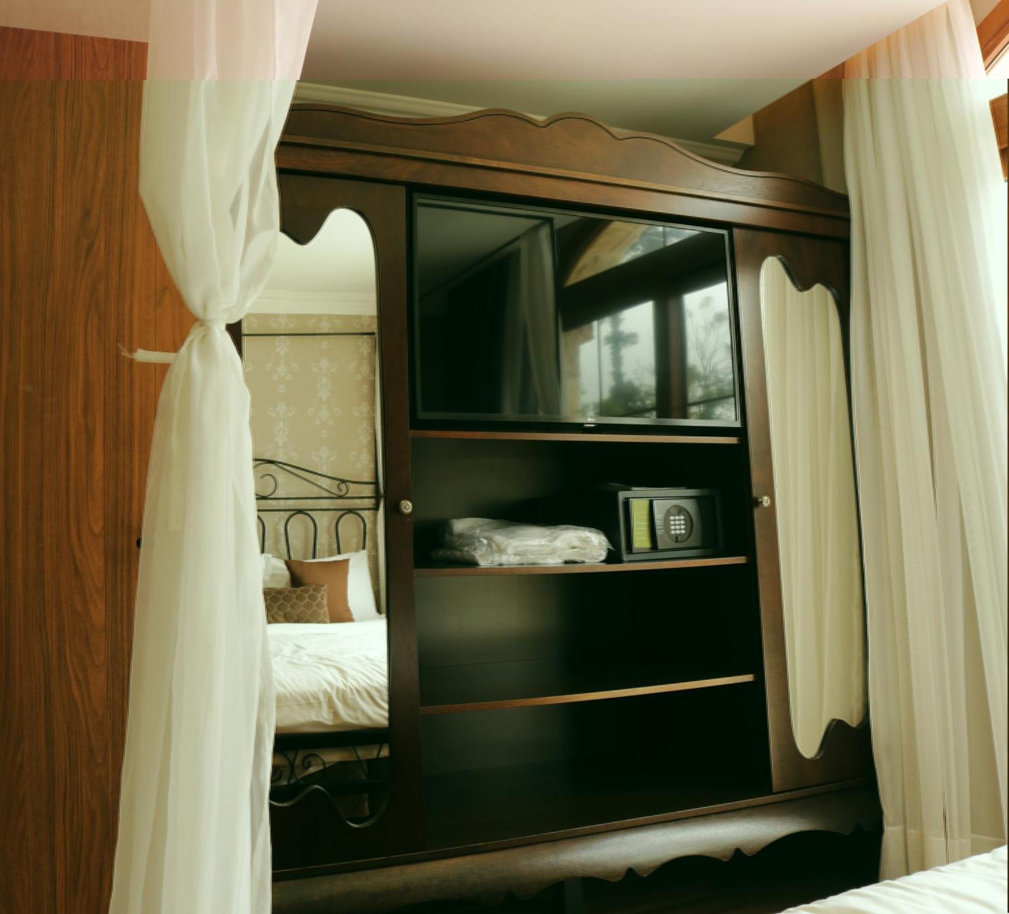 Buona Vitta Gramado Resort & Spa By Gramado Parks Exterior foto The image shows a wooden cabinet with a television mounted on the front. The cabinet has decorative edges and is paired with sheer white curtains on either side. Inside the cabinet, there are shelves, and a small safe or storage box is visible on one