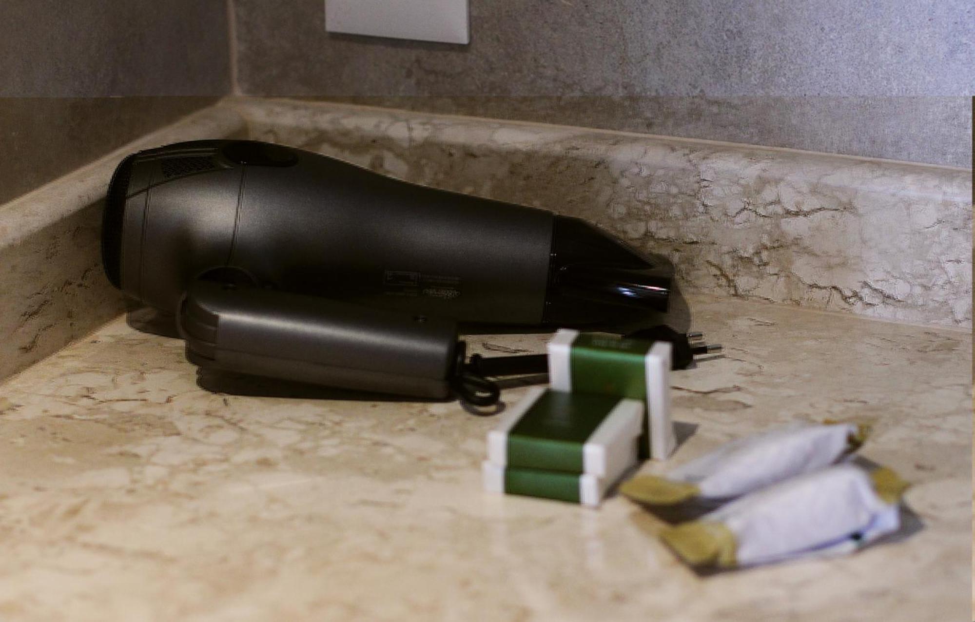 Buona Vitta Gramado Resort & Spa By Gramado Parks Exterior foto The photo shows a black hairdryer placed on a marble countertop. Next to the hairdryer, there are two wrapped items, likely toiletries, with green and white packaging. Additionally, there are two more items, also wrapped, which appear to be in simila