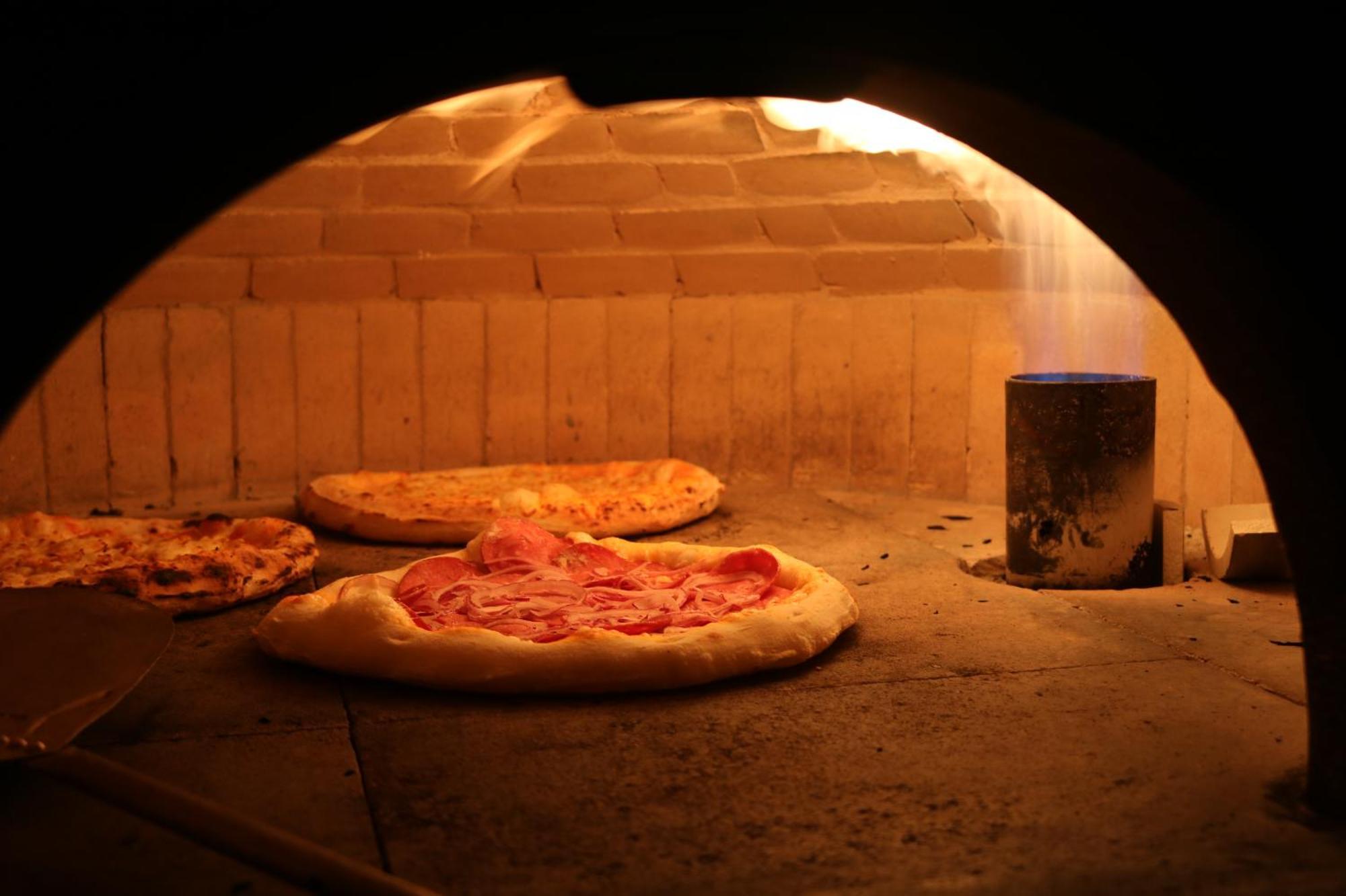 Buona Vitta Gramado Resort & Spa By Gramado Parks Exterior foto The photo shows a traditional pizza oven. Inside the oven, there are several pizzas placed on the stone surface. The pizzas appear to have various toppings, including what looks like cheese and possibly pepperoni. The oven has a warm, glowing ambianc