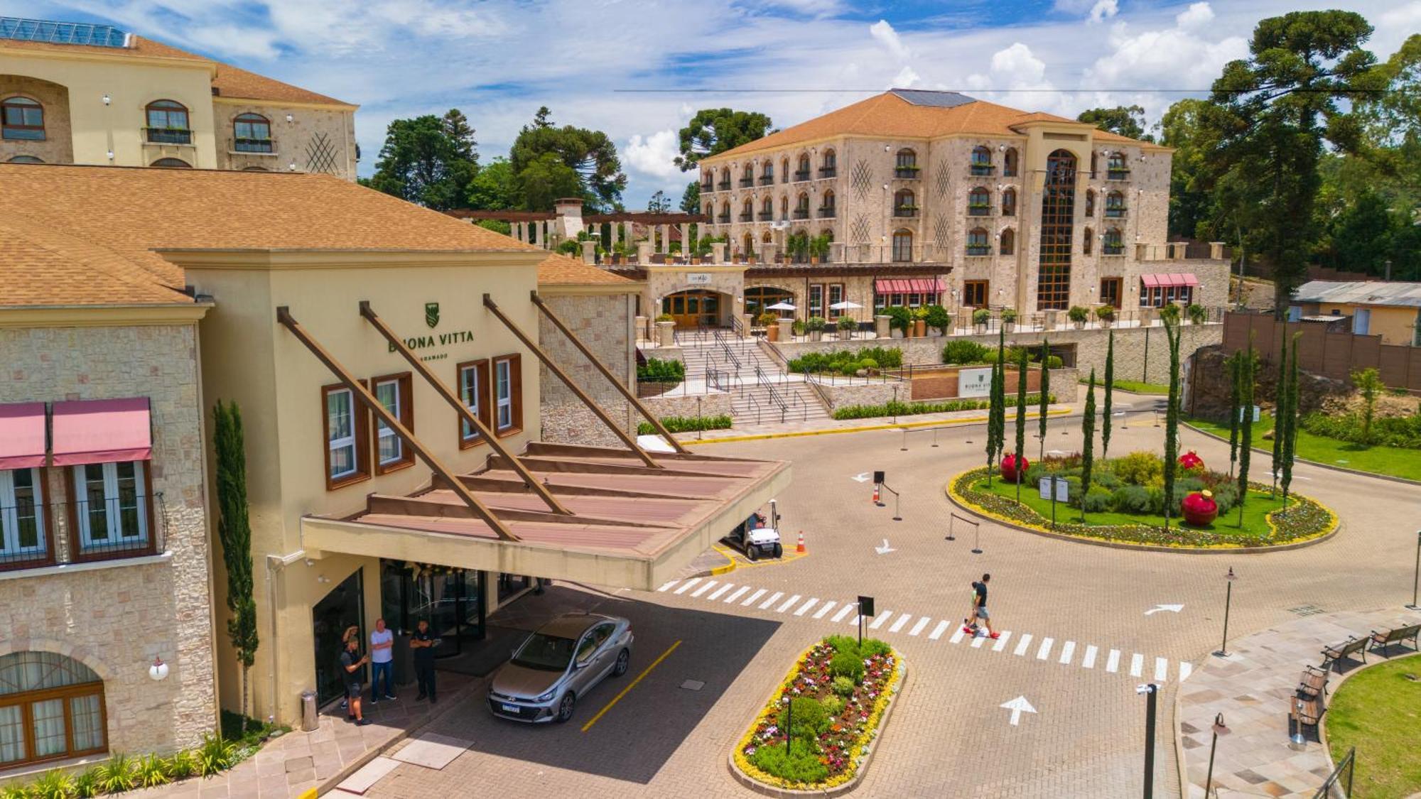 Buona Vitta Gramado Resort & Spa By Gramado Parks Exterior foto The photo shows a luxurious hotel or resort entrance, featuring a modern yet elegant architectural design. In the foreground, there is a covered entrance where vehicles are likely dropping off guests. The building has a stone facade and a welcoming e