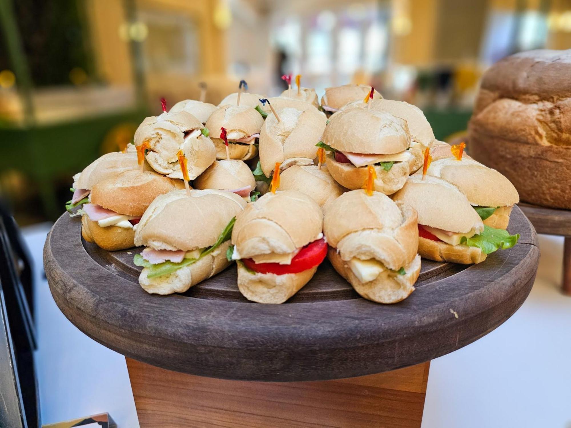 Buona Vitta Gramado Resort & Spa By Gramado Parks Exterior foto The photo shows a platter of small sandwiches, likely sliders, arranged neatly on a wooden serving tray. These sandwiches have various fillings, including what appears to be ham, lettuce, and tomato. They are garnished with colorful toothpicks, and t